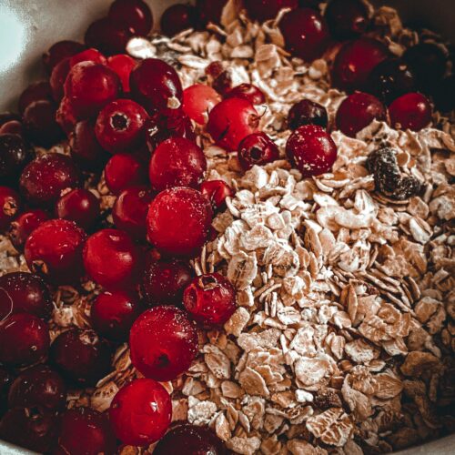 A close-up of fresh red berries and rolled oats in a bowl, perfect for breakfast.