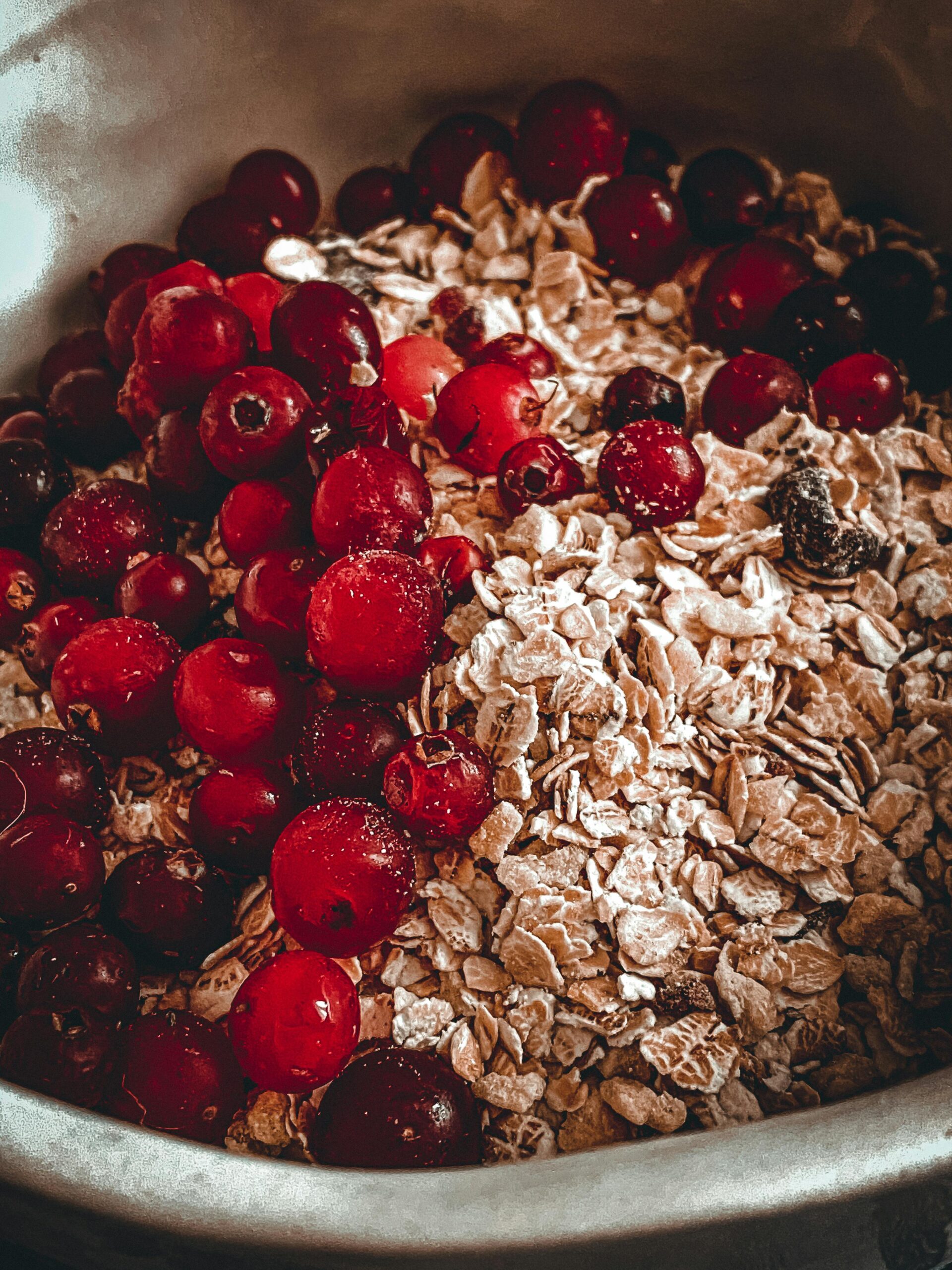 A close-up of fresh red berries and rolled oats in a bowl, perfect for breakfast.