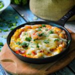 Delicious frittata with cheese and vegetables in a rustic skillet, ideal for a hearty breakfast.