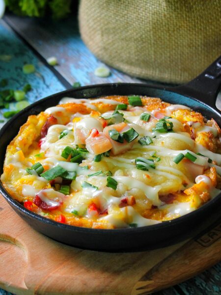 Delicious frittata with cheese and vegetables in a rustic skillet, ideal for a hearty breakfast.