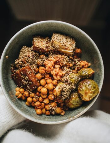 Savory vegan Buddha bowl featuring chickpeas, tofu, hemp seeds, and Brussels sprouts.