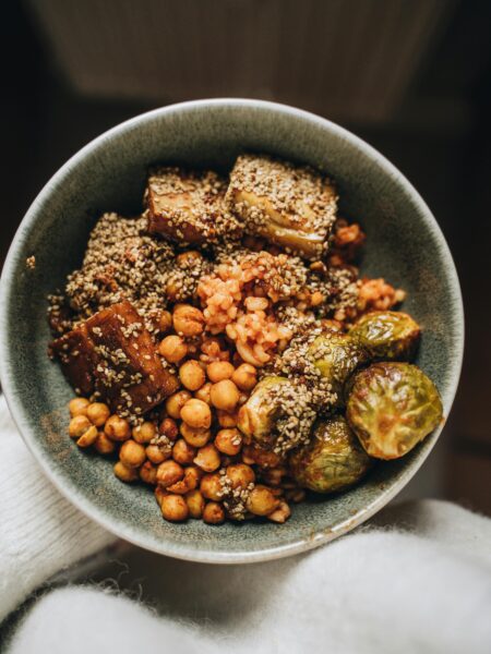 Savory vegan Buddha bowl featuring chickpeas, tofu, hemp seeds, and Brussels sprouts.