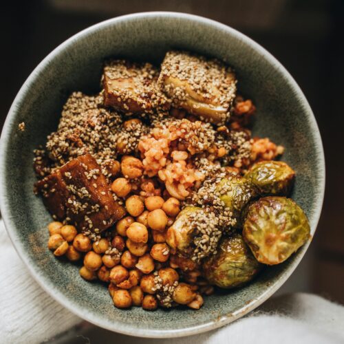 Savory vegan Buddha bowl featuring chickpeas, tofu, hemp seeds, and Brussels sprouts.