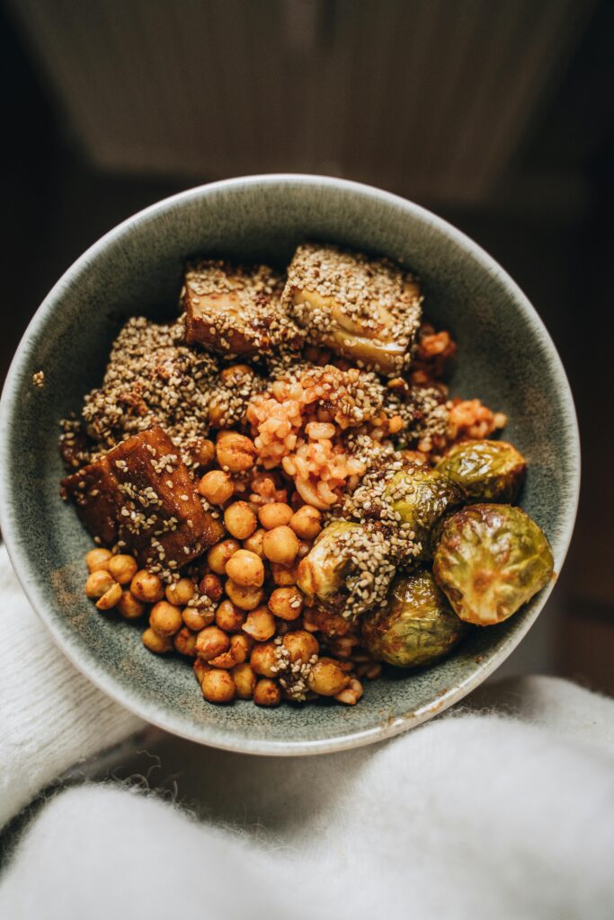 Savory vegan Buddha bowl featuring chickpeas, tofu, hemp seeds, and Brussels sprouts.
